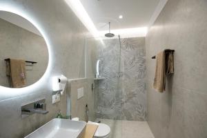 a bathroom with a shower and a sink and a mirror at Oleva Sea View Suites in Sarandë +86 photos