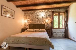 a bedroom with a bed and a stone wall at Les Gîtes Chapô Julô in Giez