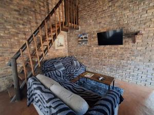a living room with couches and a tv on a brick wall at Bushveld Bliss in Marloth Park