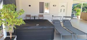 a bed in a room with chairs and a plant at Cozy White House - Near Beach Private Jacuzzi in Ksamil
