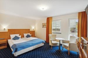 ein Hotelzimmer mit Bett, Tisch und Stühlen in der Unterkunft Hotel Blaue Ecke in Adenau