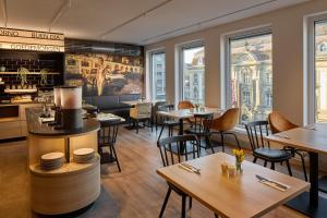 a restaurant with tables and chairs and windows at Cinema City Hotel Europaplatz Karlsruhe - Brand New Boutique Hotel 2025 - in Karlsruhe
