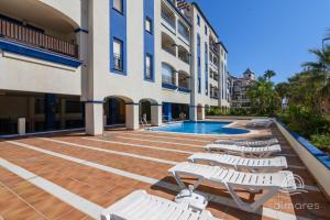 a swimming pool with lounge chairs next to a building at La Marina Solmares in Isla del Moral