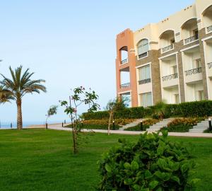 a large apartment building with a palm tree and a lawn at Oyster bey Beach Suites J1-04 in Marsa Alam