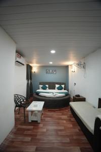 a room with a bed and a couch and a table at The Highstreet Legacy in Pune +3 photos