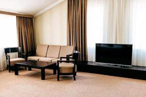 a living room with a couch and a flat screen tv at Lavina Park Hotel in Dnipro