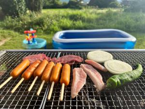 a bunch of hot dogs and meat on a grill at よんなーハウス in Kameoka