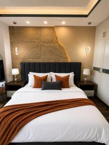 a bedroom with a large white bed with orange pillows at 1BR Luxury Apartments With Balcony & Mountains View In Elysium Tower OPP Centaurus Mall Islamabad in Islamabad
