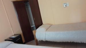 a small room with two beds and a door at B&B Guale in Gualeguaychú