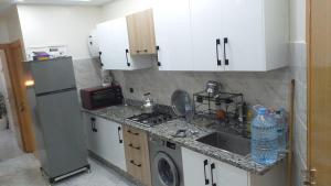 a kitchen with white cabinets and a sink and a refrigerator at Jawhara zarka in Saïdia