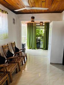 a living room with chairs and green curtains at Sana Guest in Weligama