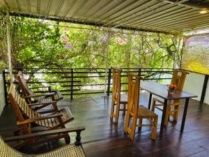a table and chairs on a porch with trees at Sana Guest in Weligama