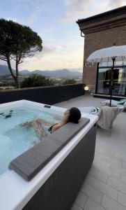 a person laying on the edge of a swimming pool at Relais Villa Flora Berta in Matelica