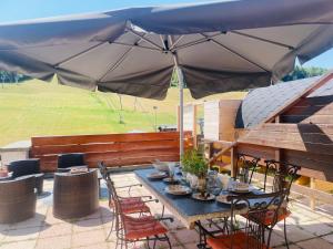 a table and chairs under an umbrella on a patio at Le Logis de Bamby in Ancelle