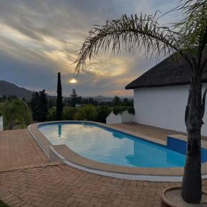 a swimming pool with a palm tree next to a building at Marianne Wine Estate in Stellenbosch