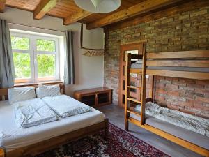a bedroom with a bunk bed and a brick wall at Chloumek in Bělá
