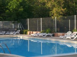 a swimming pool with lounge chairs next to a fence at Camping La Digue in Chauzon