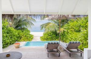 a swimming pool with two chairs and an umbrella at Sun Siyam Iru Veli - 24 Hours Premium All Inclusive Dine Around with Free Sea Plane Transfers & Exclusive Inclusions in Dhaalu Atoll