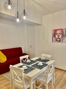 a dining room with a white table and a red couch at Iulius Mall New Residence in Iaşi +21 photos
