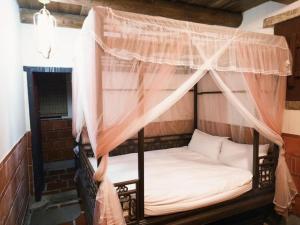 a bed with a canopy in a room at Kinmen Jinyuge Heritage B&B- Shuitou Minnan Village in Hsia-shih