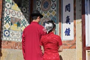 a man and a woman looking at a wall with tiles at Kinmen Jinyuge Heritage B&B- Shuitou Minnan Village in Hsia-shih +14 photos