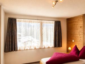 a bedroom with a large window with purple pillows at Chasa Sot-Chaunt 301 in Samnaun