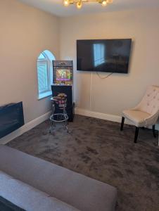a living room with a pinball machine and a chair at Withnell Stays - Apartment Three - Retro Gaming in Blackpool