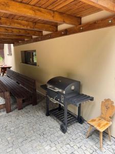 a grill in a patio with a bench and a table at Chata - TYROLEHAUSE in Martin