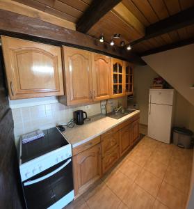 a kitchen with wooden cabinets and a stove and refrigerator at Old Oak House with pool in Maruševec +15 photos