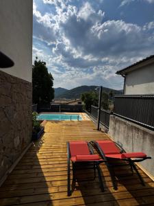 a wooden deck with two chairs and a swimming pool at el bosc in Sant Jaume de Llierca