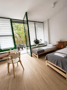 a bedroom with two beds and a chair and windows at STUDIO LEŚNE z DUŻYM TARASEM nad Zalewem in Serock