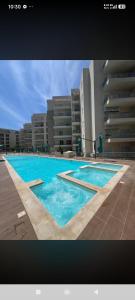 a large swimming pool with blue water in front of buildings at L'escapade in Sousse