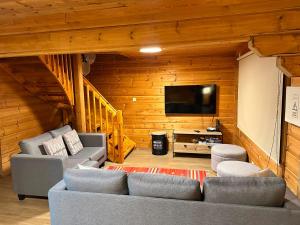 a living room with two couches and a flat screen tv at Chale do Avô Chico Penhas da Saúde in Penhas da Saúde
