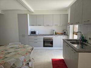 a kitchen with white cabinets and a sink and a table at Casa Vacanze Merion in Piticchio