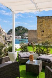 a patio with chairs and tables and a view of the ocean at Chiaia Di Rose Seaside Suite in Sant'Angelo D'Ischia