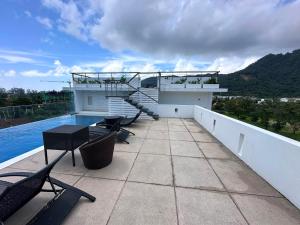 a balcony with chairs and a staircase on a house at Yenna Apt in Kamala Beach