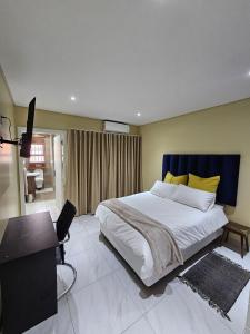 a bedroom with a large bed and a desk at Posimuma Guesthouse Boutique in Centurion +9 photos