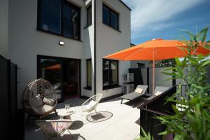 an outdoor patio with chairs and an orange umbrella at Capsule Retro Balnéo - Sauna - Billard -Switch 2 in Limelette