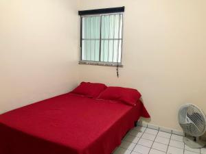 a red bed in a white room with a window at Casa três quartos em condomínio in Garanhuns