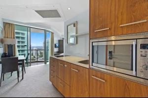 a kitchen with wooden cabinets and a microwave and a table at Stunning City View Beachfront Apartment in Gold Coast