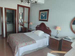 a bedroom with a large bed and a bathroom at Pensión Chiquilla in O Grove