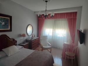 a bedroom with a bed and a desk and a chair at Pensión Chiquilla in O Grove +10 photos