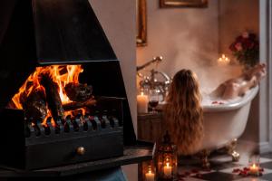 a woman taking a bath in a bath tub with a fireplace at Goblin's Creek in St. Helena Bay