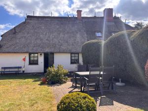 a house with a table and chairs in the yard at Alte Fischerhütte Darss in Wieck