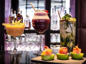 two cocktails sitting on a table with fruit in vases at Sofitel Strasbourg Grande Ile in Strasbourg