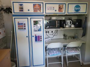 a small kitchen with two chairs and a refrigerator at Mudeford Swans in Christchurch