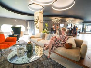 a woman sitting on a couch in a living room at Pullman Bordeaux Lac in Bordeaux