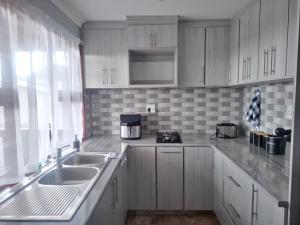 a kitchen with white cabinets and a sink and a window at The Cottage Eplazini in Port Shepstone