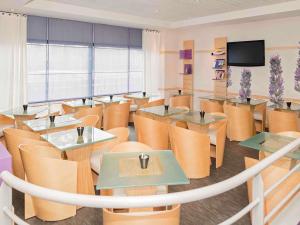 a restaurant with tables and chairs and a flat screen tv at ibis Metz Centre Gare in Metz