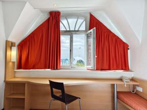 a window with red curtains and a desk with a chair at ibis Metz Centre Gare in Metz